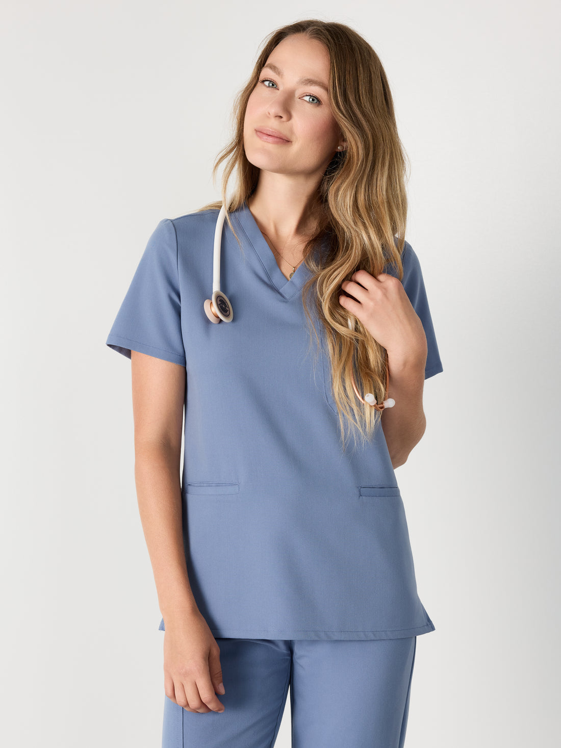 Person wearing a blue scrub set with a stethoscope on a white background